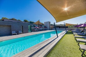 A swimming pool with lounge chairs and umbrellas, surrounded by a wooden deck and artificial grass. - Corsica Haven With Garden (Lecci)