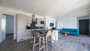 A modern kitchen with a central island, bar stools, a blue sofa, and a dark door. - Corsica Haven With Garden (Lecci)