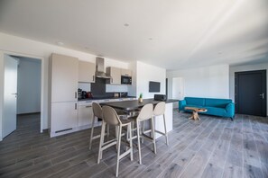 A modern kitchen with a central island, bar stools, a blue sofa, and a dark door. - Corsica Haven With Garden (Lecci)