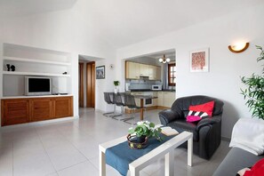 Ein modernes Wohnzimmer mit einer Couch, einem Couchtisch und einem Fernseher.