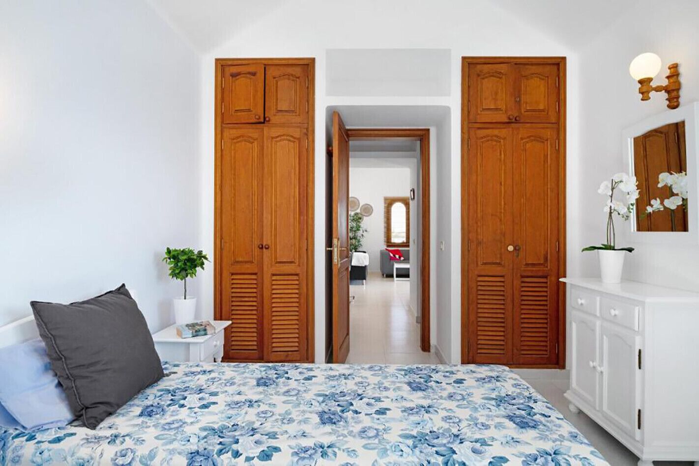 A bedroom with a bed, a nightstand, a dresser, and a large wooden wardrobe.