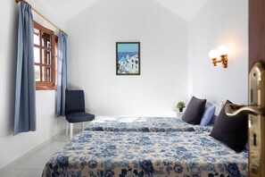 Ein Schlafzimmer mit zwei Betten, einem fenster mit Vorhängen, einem Sessel, einer Wandleuchte und einem gerahmten Bild.