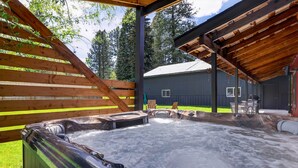 A hot tub area with a wooden deck and a covered seating area.