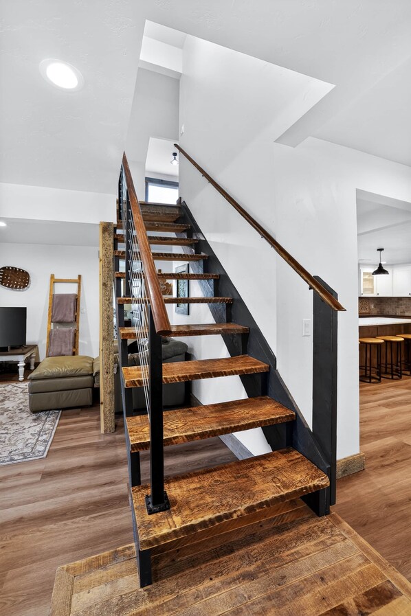 Una escalera de madera con barandillas negras que conduce a un piso superior.