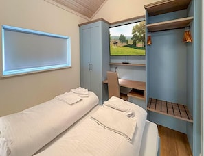 A bedroom with two single beds, a desk, a television, and a wardrobe. - Ferienhaus mit Sauna und Whirlpool in Bad Bevensen (Bad Bevensen)
