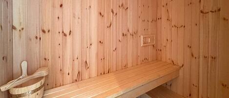 A sauna room with wooden walls and a bench.