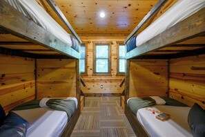Eine Holzhütte mit zwei Etagenbetten, einem Mittelbalkon und Holzboden.