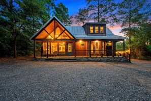 Una cabaña de madera con techo inclinado, ventanas amplias y base de piedra.