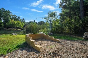 Eine Holzterrasse mit Steinrand, umgeben von Kiesfläche und Grünpflanzen.