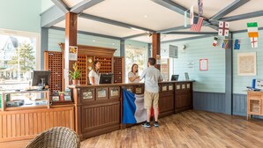 A reception area with a wooden counter, a computer, and a potted plant. - House Near the Lake and Golf Course (Fort-Mahon-Plage)