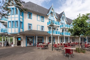 A traditional European-style building with a terrace cafe, outdoor seating, and a view of the water. - House Near the Lake and Golf Course (Fort-Mahon-Plage)