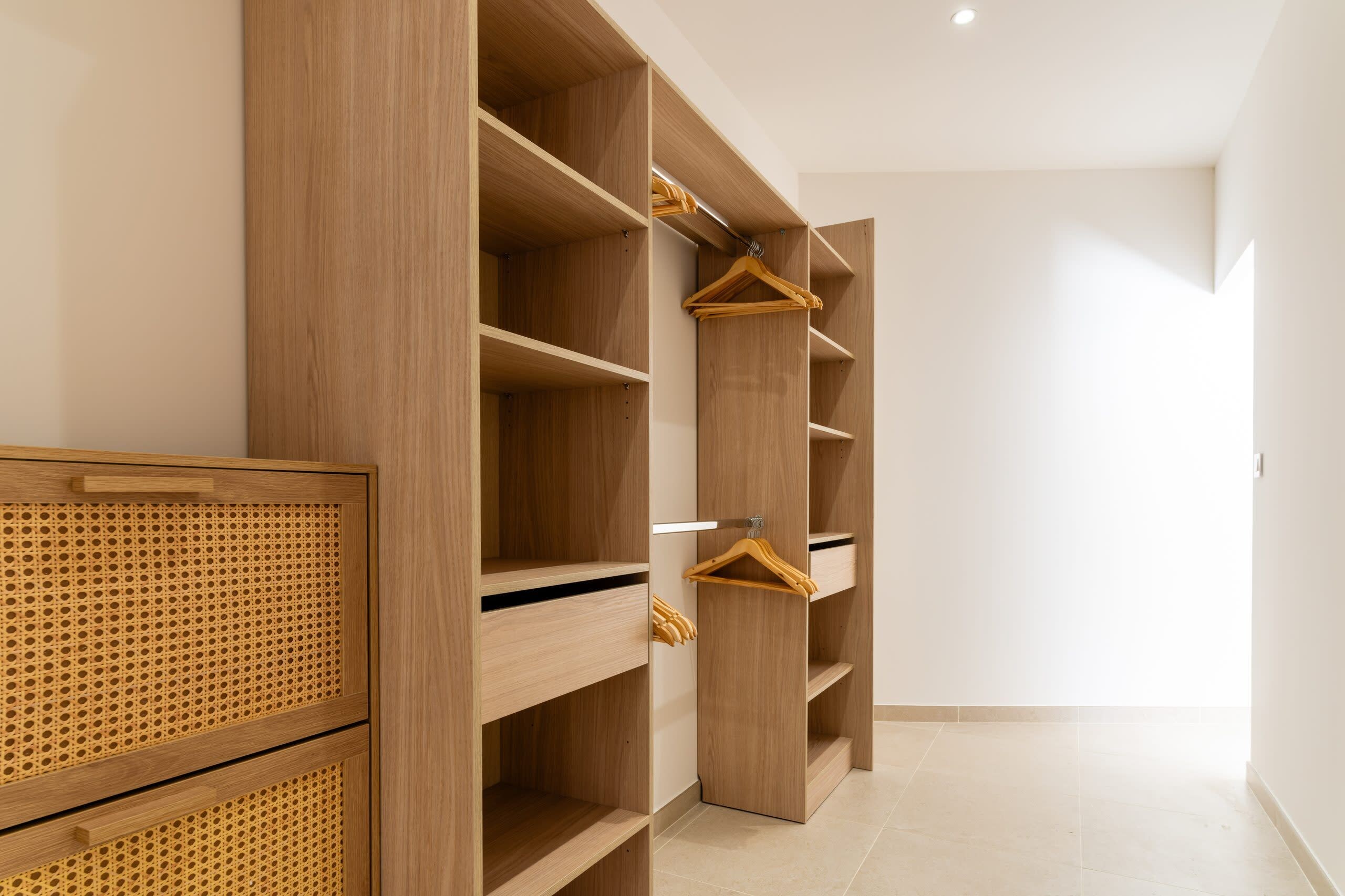 A walk-in closet with multiple wooden shelves and a rattan panel.