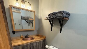 A bathroom with a wooden vanity, a white toilet, a mirror with lights, and a towel rack. - Perfect 2-bedroom apartment in wonderful Wyarno for your stay (Wyarno)