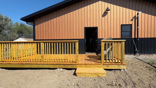 A building with a wooden exterior, a black door, and a wooden deck leading to the entrance. - Perfect 2-bedroom apartment in wonderful Wyarno for your stay (Wyarno)