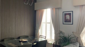 Ein modernes Wohnzimmer mit einem Glastisch, einem grauen Sofa und einer gestreiften Wand.