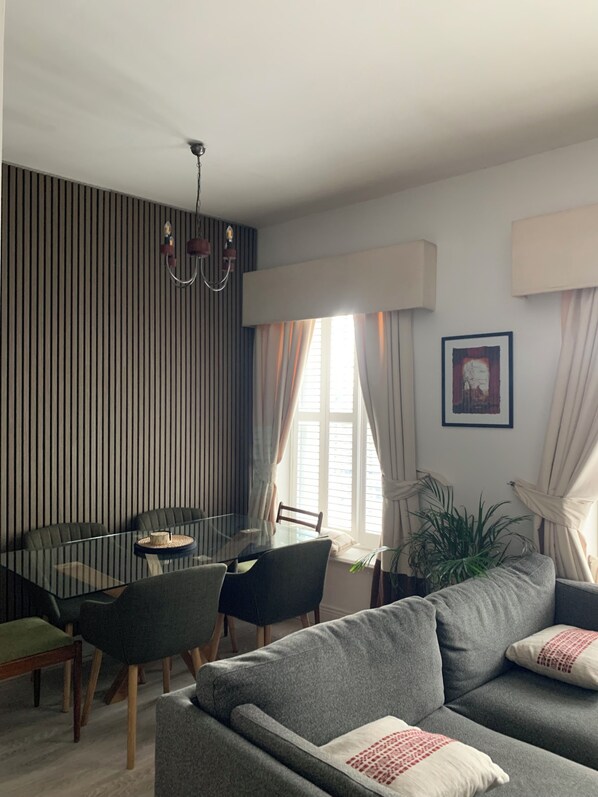 Una sala moderna con una mesa de vidrio, un sofá gris y una pared a rayas.