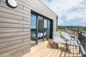 Un edificio moderno con balcón, cama y vistas del paisaje.