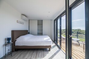 A bedroom with a bed, bedside table, and a view of a balcony. - Sun-drenched Corsican Flat (Lecci)