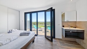 Quarto com cama, banheiro com pia e varanda com cadeiras.