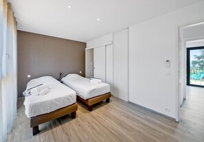 A modern hotel room with two beds, a wooden floor, and a large sliding door leading to a balcony. - Sun-drenched Corsican Flat (Lecci)