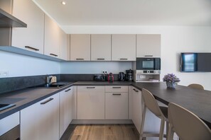 Una cocina moderna con encimera oscura, armarios de colores claros, microondas, tostadora y cafetera.