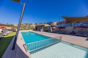 A swimming pool with a wooden deck, lounge chairs, and umbrellas. - Sun-drenched Corsican Flat (Lecci)