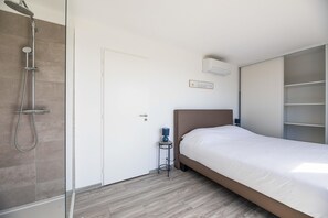 Un dormitorio con ducha, cama, mesita de noche y armario.