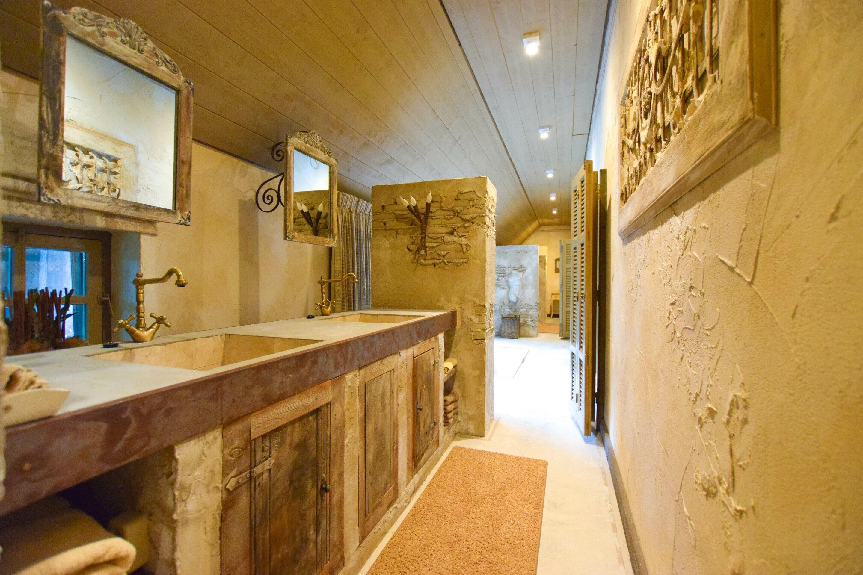Un baño con tocador de madera, un espejo grande y una pared decorativa de piedra.