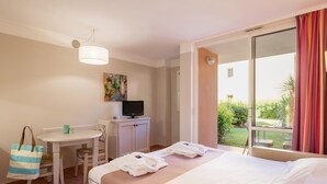 Ein Hotelzimmer mit Bett, Schreibtisch, Fernseher und Blick auf einen Garten.