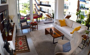 En moderne stue med sofa, lænestole, sofabord og et spiseområde med bænk og stole.