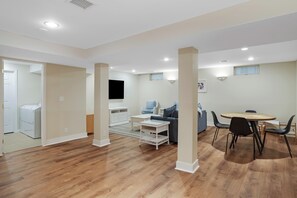A spacious living area with a wooden floor, a round dining table, and a sofa.