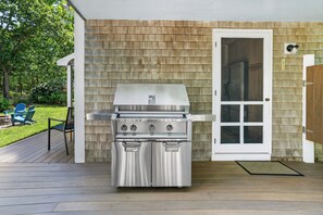 An outdoor grill with a white door and a wooden deck.