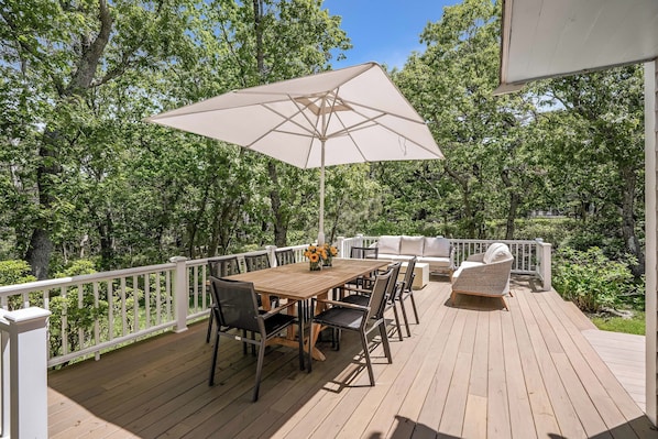 A wooden deck with a table, chairs, and a large umbrella.