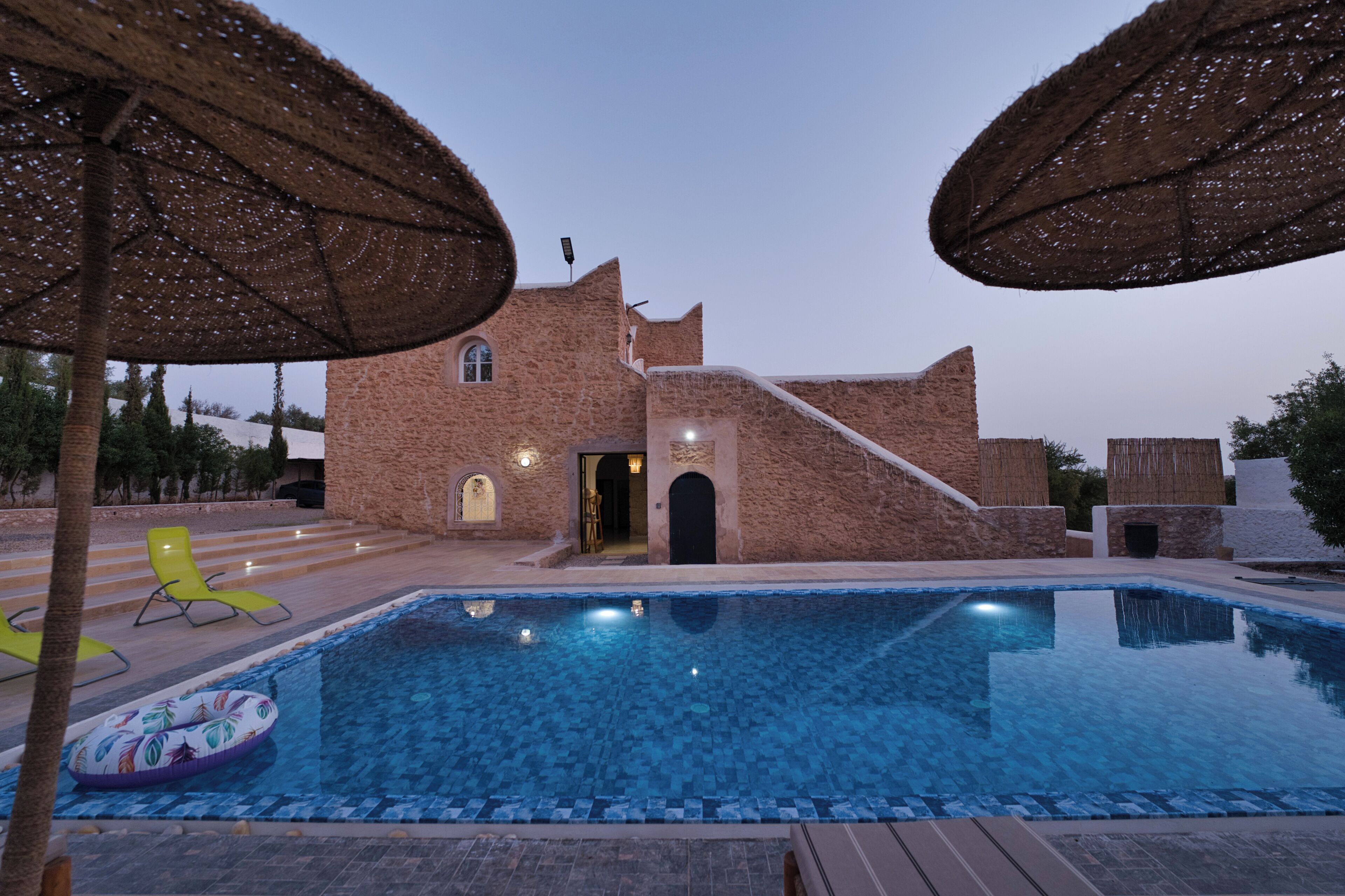 Uma piscina com um edifício de pedra ao fundo.
