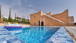 A swimming pool with a checkered edge, a building with a distinctive architectural style, and a clear sky. - Villa Aisha . Private Pool & Garden Retreat – 20 min from Essaouira (Essaouira)