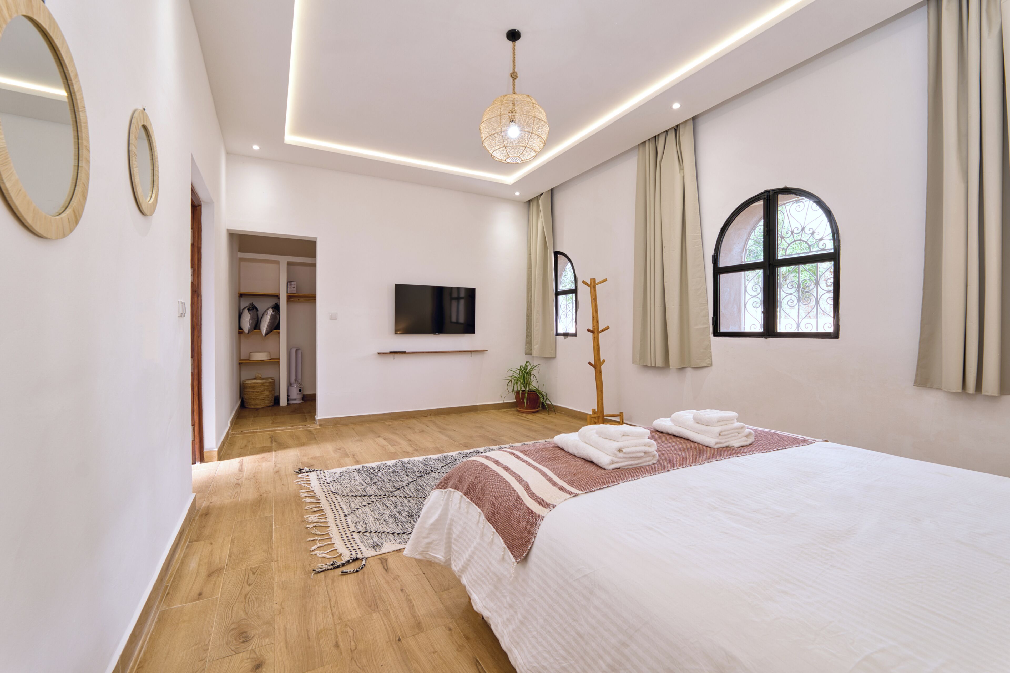 Une chambre moderne avec un grand lit, un téléviseur à écran plat, un plancher en bois et une fenêtre avec des rideaux.