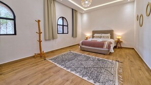 A bedroom with a bed, a standing lamp, a coat rack, and a window. - Villa Aisha . Private Pool & Garden Retreat – 20 min from Essaouira (Essaouira)