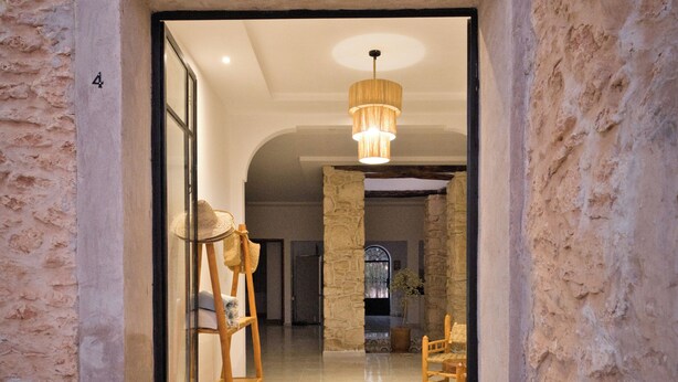 A stone-walled corridor leading to a room with a chandelier, a wooden ladder, and a seating area. - Villa Aisha . Private Pool & Garden Retreat – 20 min from Essaouira (Essaouira)