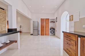 Eine moderne Küche mit einer Steinwand, einem Kühlschrank, einer Waschmaschine, Holzschränken und einer schwarzen Arbeitsplatte.