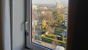 Una ventana con vistas a un paisaje urbano, incluyendo edificios y árboles.
