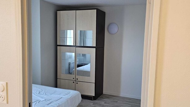 Un dormitorio con cama, armario y un reloj de pared redondo.