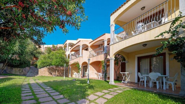 A hotel with a courtyard, outdoor seating, and a stone pathway. - Stunning Sea View Apartment for 4 (Badesi)