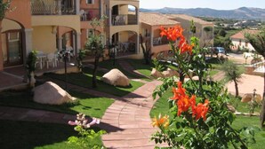 A hotel with multiple balconies, outdoor seating, and a landscaped garden. - Stunning Sea View Apartment for 4 (Badesi)