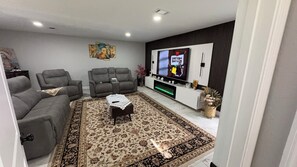 A living room with a sofa set, a coffee table, a TV, and a decorative wall piece.