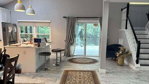 Un vaste espace de vie comprenant une cuisine, une table à manger et un escalier menant à un autre niveau.