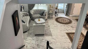 Un salon comprenant un canapé, un pouf et une statue décorative.