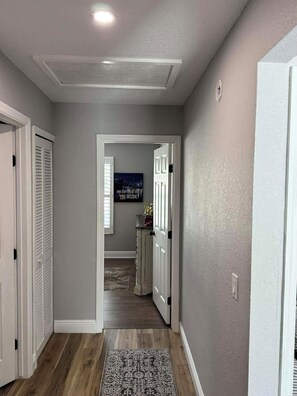 A hallway with a wooden floor, a patterned rug, and a door leading to a room with a view.