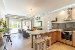Una cucina moderna con isola centrale, elettrodomestici in acciaio inossidabile e un lampadario.