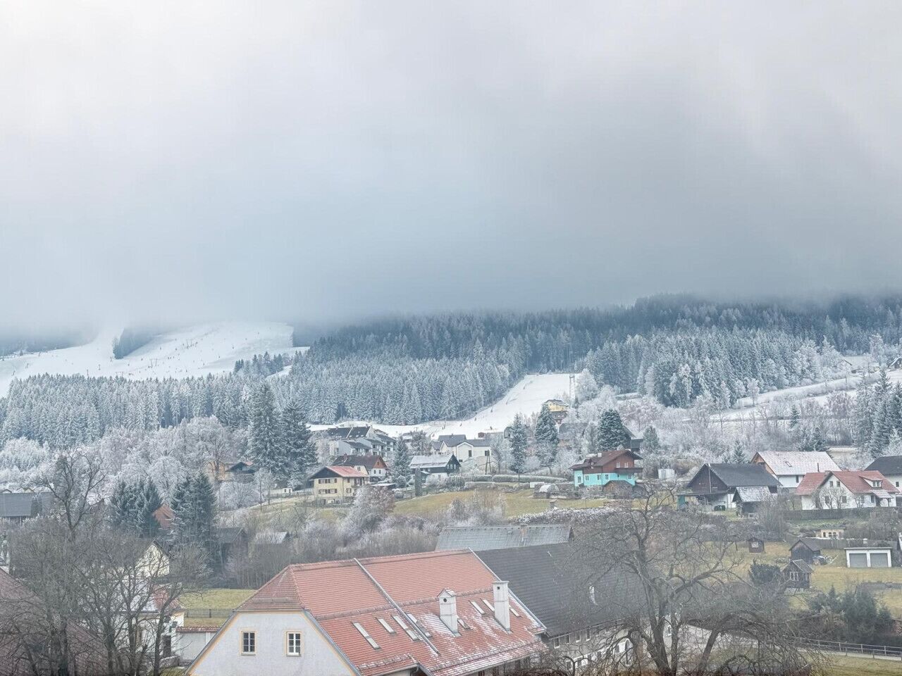 A rural village with houses, a church, and a snow-covered landscape.