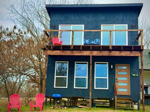 A two-story cabin with a balcony, a door, and windows.